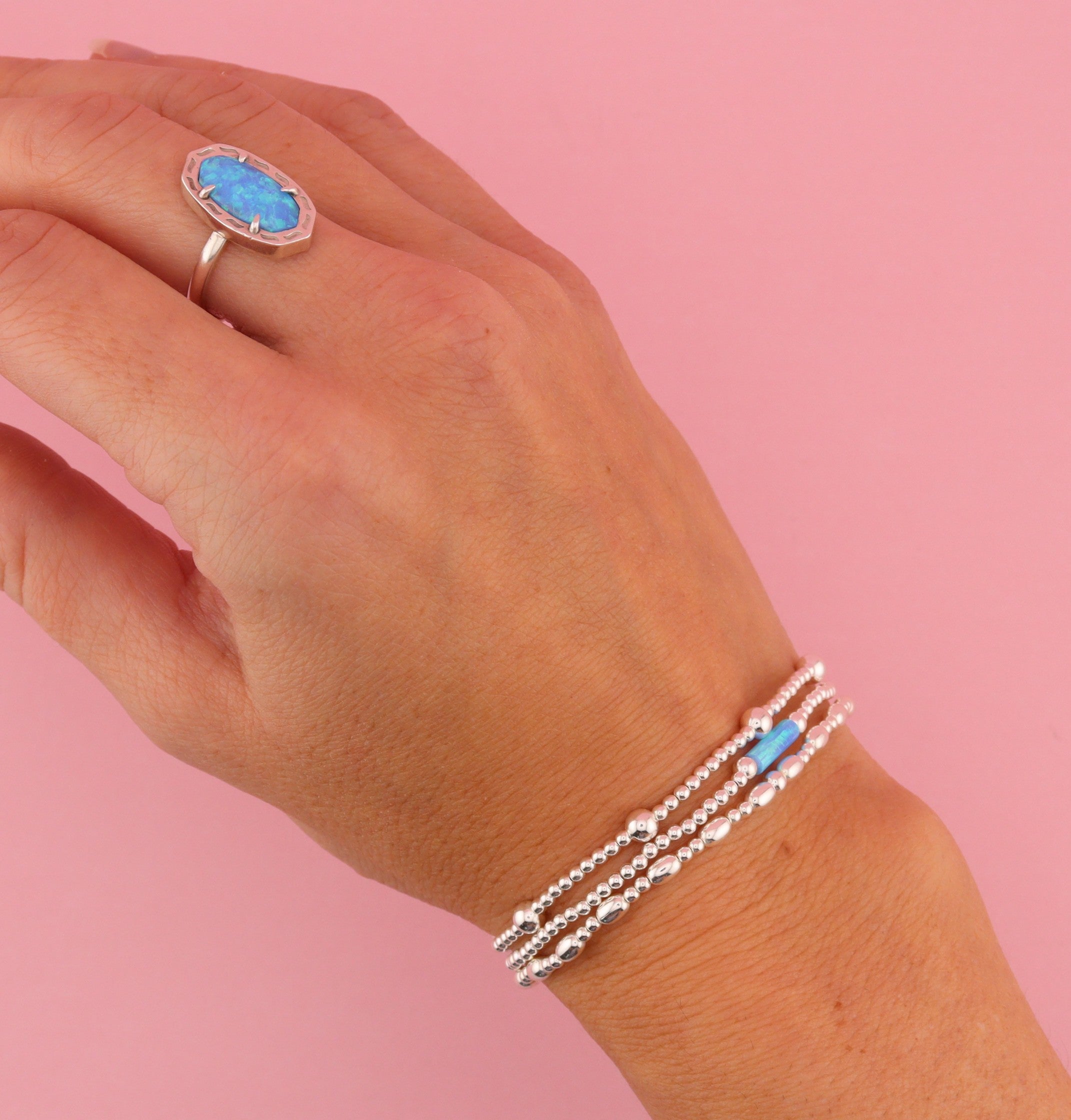 Silver beaded bracelet on a wrist over a white background