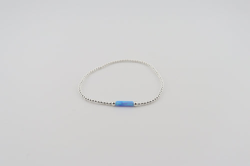 Silver bracelet with a blue bead on a light gray background