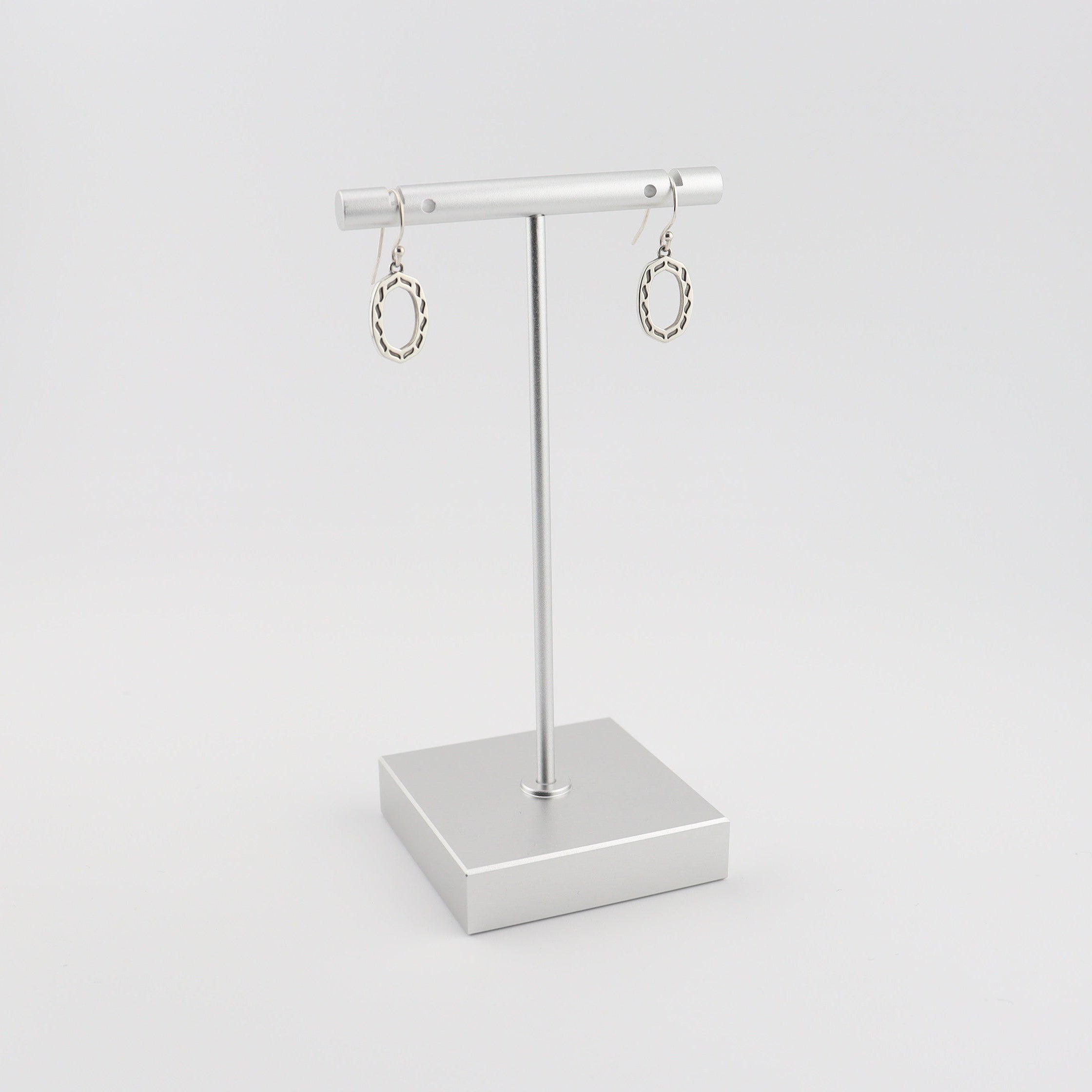 Silver earrings on a stand against a white background