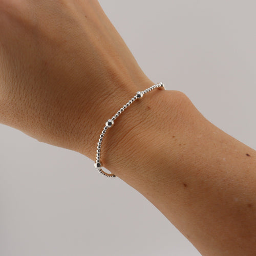 Silver bracelet on a wrist with a neutral background