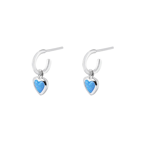 Silver hoop earrings with heart-shaped charms with blue heart stones on a white background